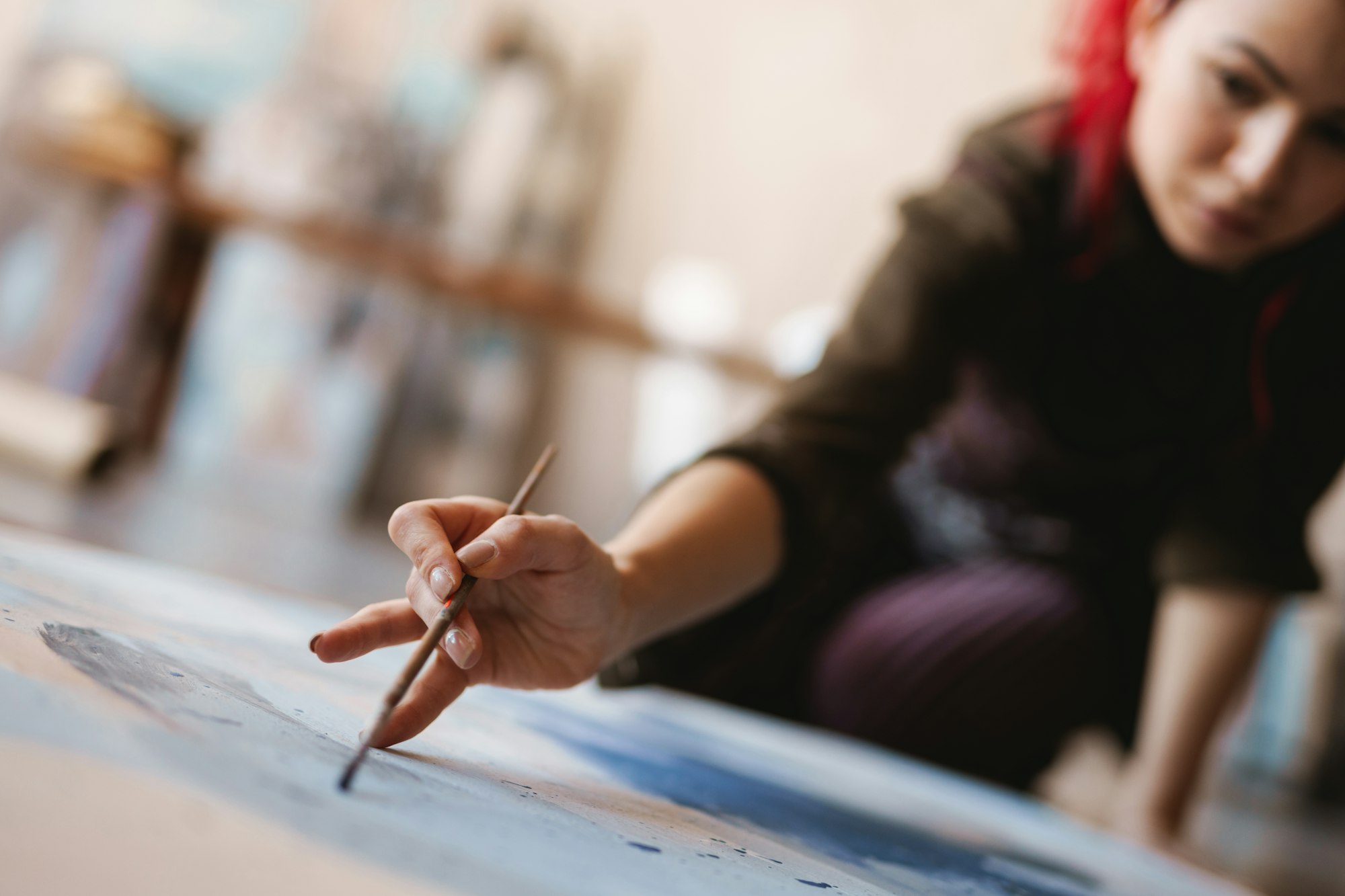 Young woman artist painting in studio